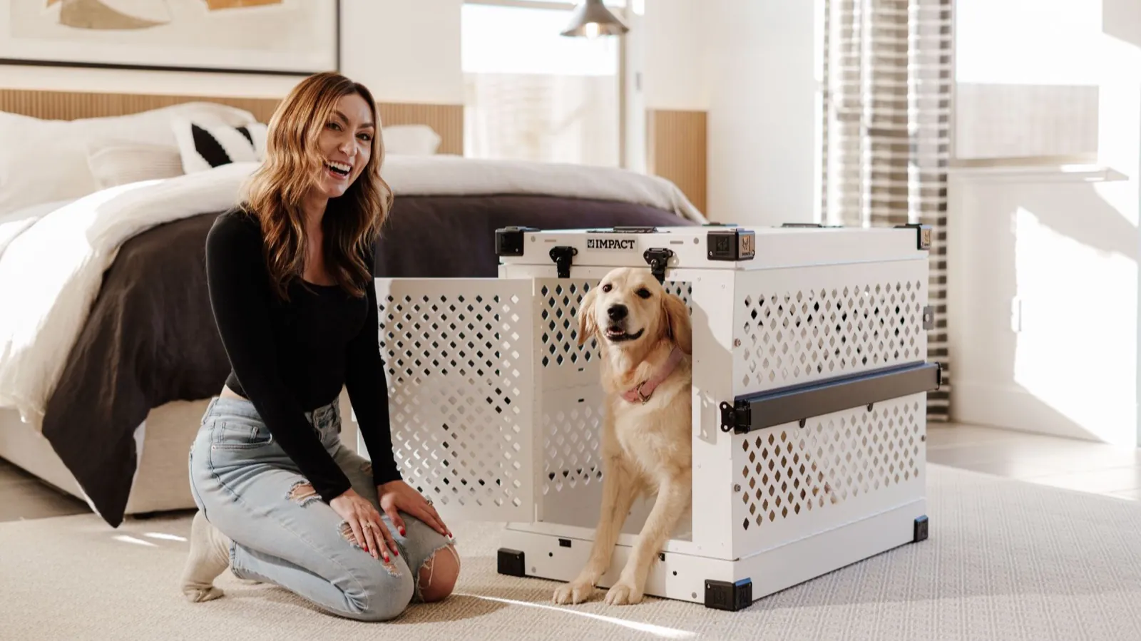 A golden retriever relaxed in an open crate at the foot of the bed